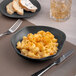 An Ariane Earth charcoal grey porcelain bowl filled with macaroni and cheese on a table.
