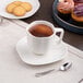 A warm white porcelain cup of coffee and cookies on a table.