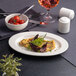 An oval white embossed wide rim platter displayed on a table setting.