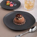 An Ariane Earth charcoal grey porcelain dessert plate with chocolate on it and a spoon.