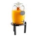 A black pinewood beverage dispenser stand holding a glass drink dispenser filled with orange liquid.