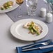 An 8 1/4 inch warm white round wide rim flat porcelain plate with food served on it.