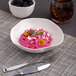 A warm white Ariane Earth porcelain bowl filled with pink pasta and blackberries.