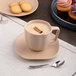 A dark sand dots porcelain cup filled with coffee on a table with cinnamon sticks and cookies.