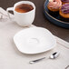 A white porcelain saucer with a cup of coffee and a cupcake.