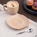 A dark sand dots porcelain saucer with a cup of coffee and a cupcake on a table.