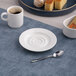 A round, warm white porcelain espresso cup saucer with a wide rim.
