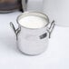 An American Metalcraft milk can creamer filled with white liquid.
