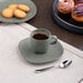 An Ariane mist green dots espresso cup filled with coffee on a table with cookies.