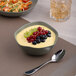 A bowl of fruit and vegetable salad in an Ariane mist green dots porcelain bowl.