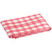 A folded red and white gingham vinyl table cover with a flannel back.