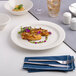 A round, warm white porcelain banquet plate with a medium rim.