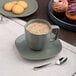 A Mist Green Dots Porcelain cup of coffee on a table with cookies.