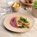 A plate of food with fish and vegetables on an Ariane Earth Dark Sand Dots porcelain plate on a marble table.