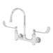 A chrome T&S surgical sink faucet with wrist action handles and a gooseneck spout.