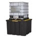 A large black indoor pallet with forklift pockets holding a white IBC container secured by a metal cage.