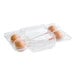 A clear plastic container holding four pumpkin cake pops with orange coating and yellow sprinkles.