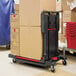 A black Rubbermaid convertible utility cart full of boxes.