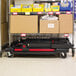 A Rubbermaid black utility cart with cardboard boxes on it.