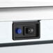 A close-up view of a control panel with a power switch and a blue indicator light on an undercounter ice machine.