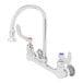 A T&S chrome wall mounted surgical sink faucet with 4" wrist action handles and 8" adjustable centers.