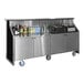 A stainless steel and black laminate portable back bar with wheels, featuring two locking storage compartments and a countertop stocked with beverages and bar supplies.