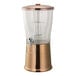 A 3-gallon round cold beverage dispenser with a metallic rose gold stainless steel base, clear Tritan plastic container, hands-free spigot, and an infuser tube.