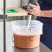 A translucent 12-quart round food storage pail with blue measurement markings and a metal bail handle.