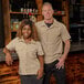 A women's khaki short sleeve work shirt with button front and chest pockets.