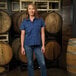 A women's navy blue short sleeve work shirt in size medium, modeled in front of wooden barrels.