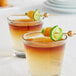A short glass of layered cocktail garnished with a gold bamboo ball pick holding a slice of lime and an orange piece.
