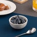 A small white embossed porcelain bowl filled with blueberries.