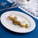 A white oval embossed wide rim porcelain platter displaying three elegantly plated appetizers.
