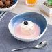 A blue and white ombre round porcelain coupe bowl filled with a dessert and pink sauce.