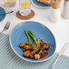 A blue oval porcelain plate with a coupe design, measuring 10 1/4 by 7 inches.