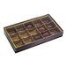 A rectangular brown and gold candy box with a transparent lid, containing 15 cavities, some of which hold chocolate candies.
