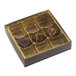 A brown and gold 9-cavity candy box with a transparent lid, containing three assorted chocolates.