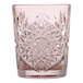 A pink cut-glass rocks glass with an intricate starburst pattern.