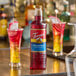A 1-liter plastic bottle of Torani Dragon Fruit flavoring syrup displayed on a bar counter.