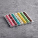 A plastic tray containing an assortment of colorful mini macarons in various flavors.