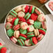 A plate of assorted Christmas-themed macarons in red, green, and white colors with festive decorations.