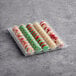 A plastic tray containing 50 assorted Christmas-themed macarons in festive colors and patterns.
