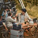 A portable lithium-ion power station placed on a stack of metal cases at a campsite.