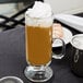 An 8 oz. glass coffee mug with a handle, filled with coffee and topped with whipped cream.