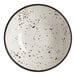 A white round coupe bowl with black speckled pattern and a dark rim.