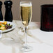 A clear 6 oz. flute glass filled with sparkling wine, placed on a marble table.