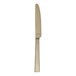 A gold-colored stainless steel dinner knife with a straight handle and a slightly serrated edge.