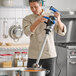 A chef using a Waring WSB700X Big Stik EvolutionX 21-inch electric variable-speed heavy-duty immersion blender in a commercial kitchen.