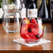 A clear, round Libbey Orbital 16.75 oz. stackable tumbler filled with a fruit beverage, placed on a napkin.