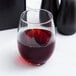 A clear Libbey 15 oz. stemless wine glass partially filled with red wine.